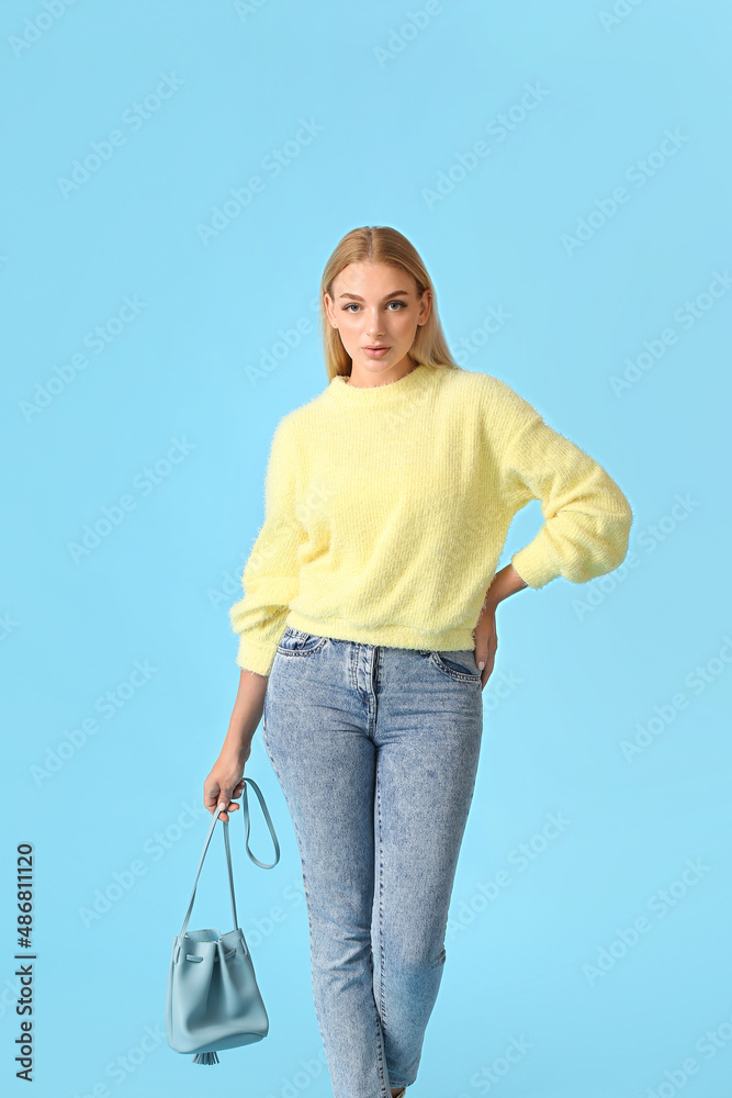 Fashionable young woman in stylish jeans on color background