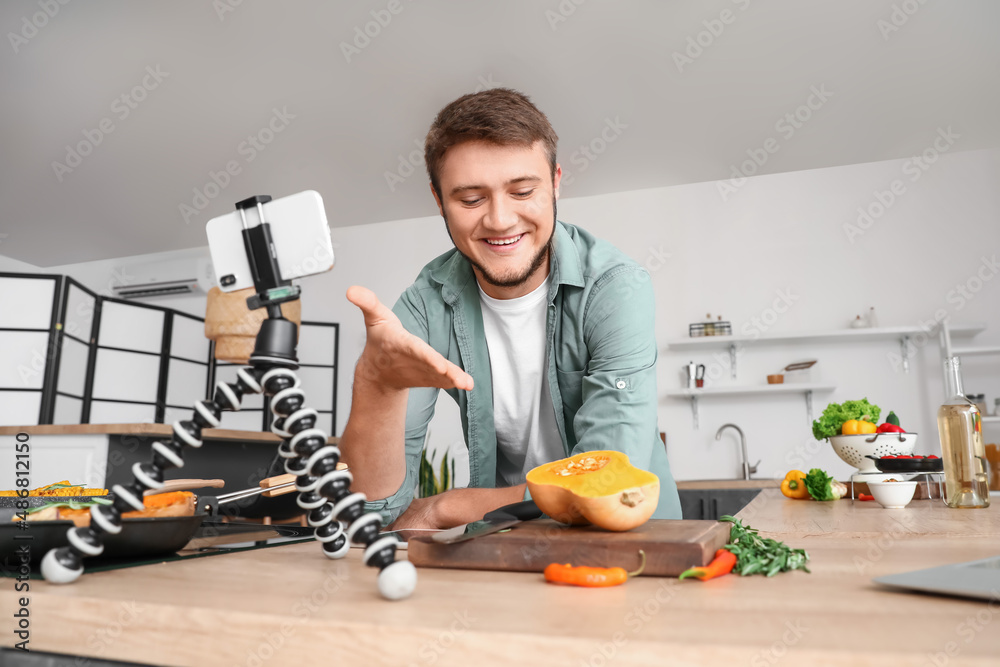 Young man watching cooking video tutorial in kitchen