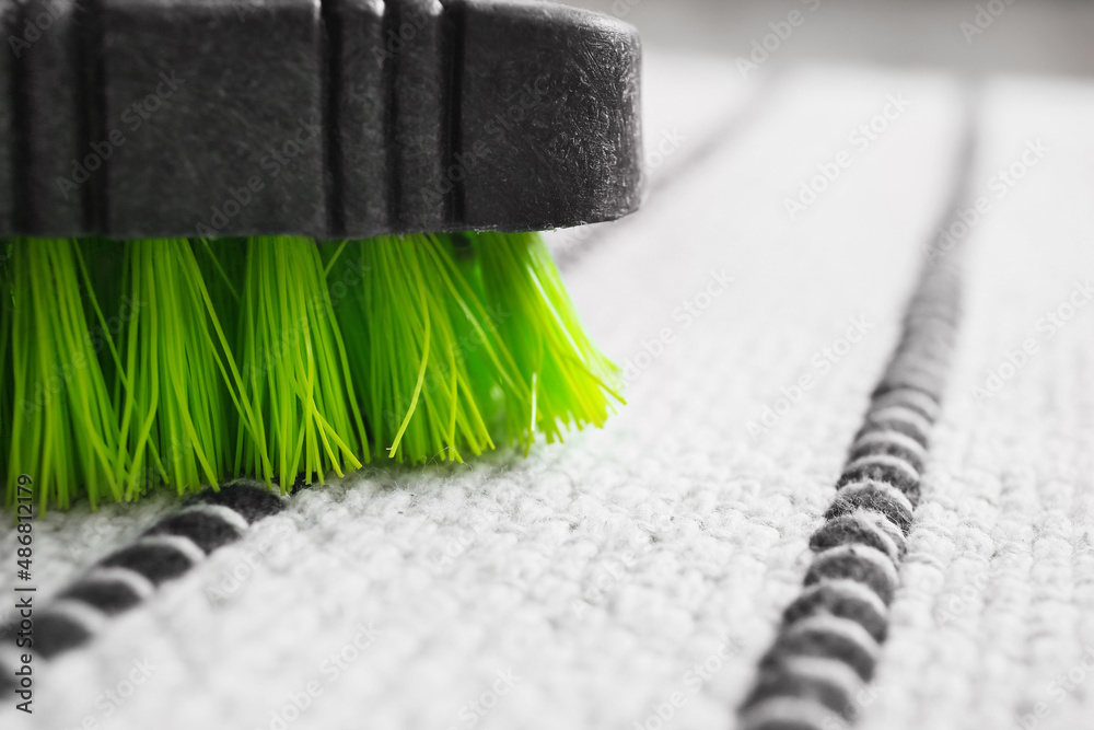 Cleaning brush on striped carpet in room, closeup