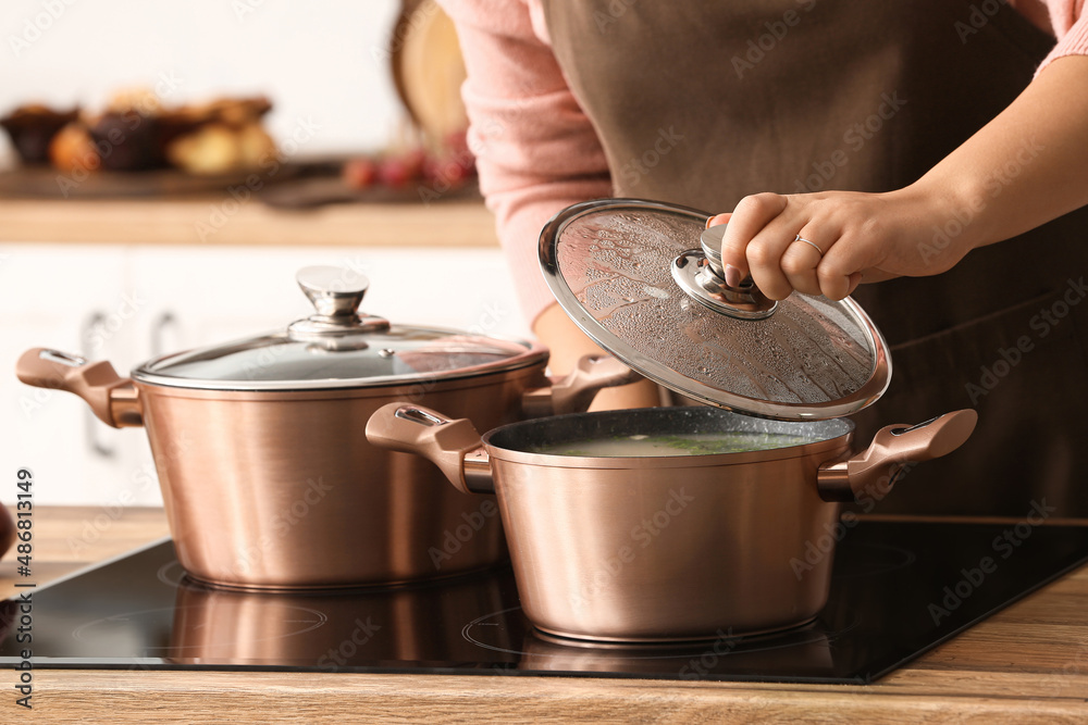 Woman cooking in copper pots at home, closeup