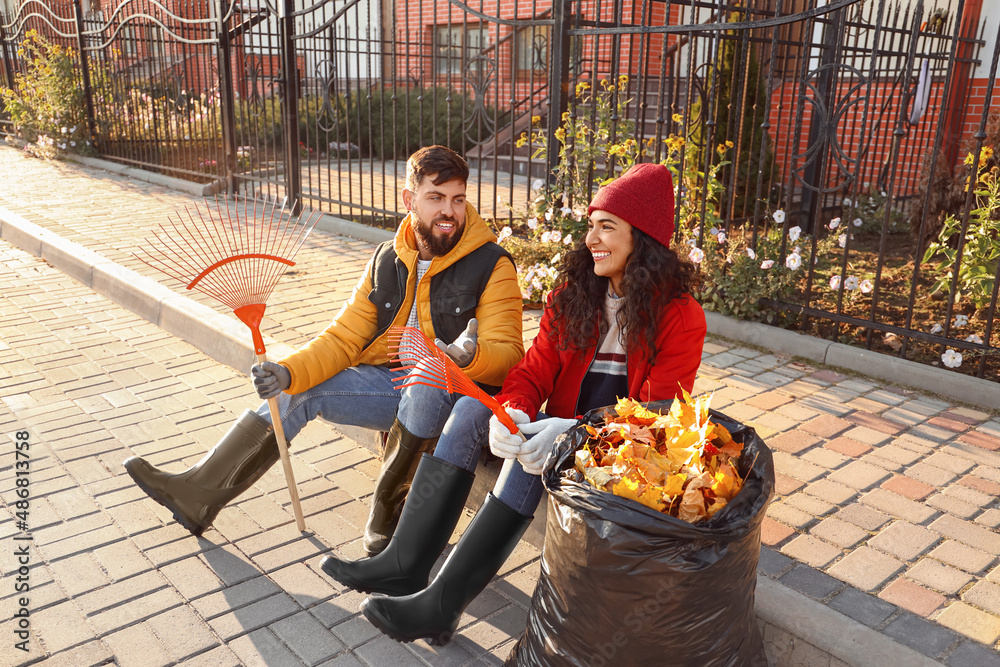 Couple resting after gathering autumn leaves outdoors