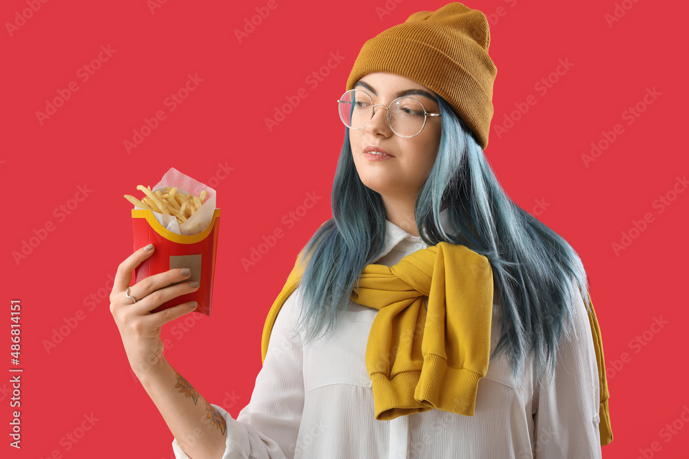 Young woman with unusual hair and french fries on color background