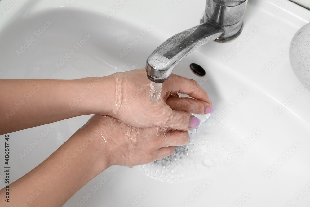 Woman washing her hands under running water from tap, closeup