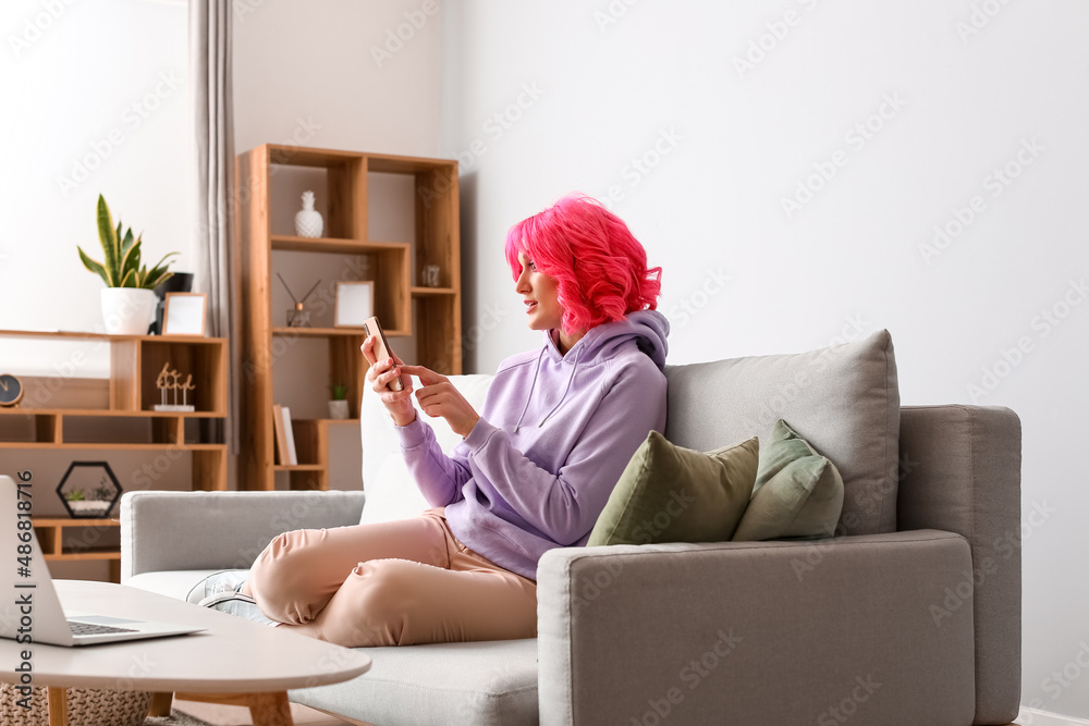 Shocked young woman with mobile phone at home