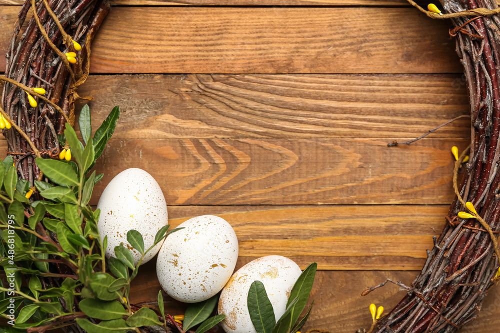 Beautiful Easter wreath and eggs on wooden background, closeup