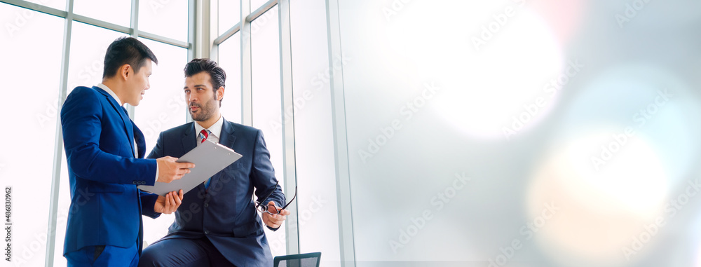 Two business people talk project strategy at office in widen view meeting room. Businessman discuss 