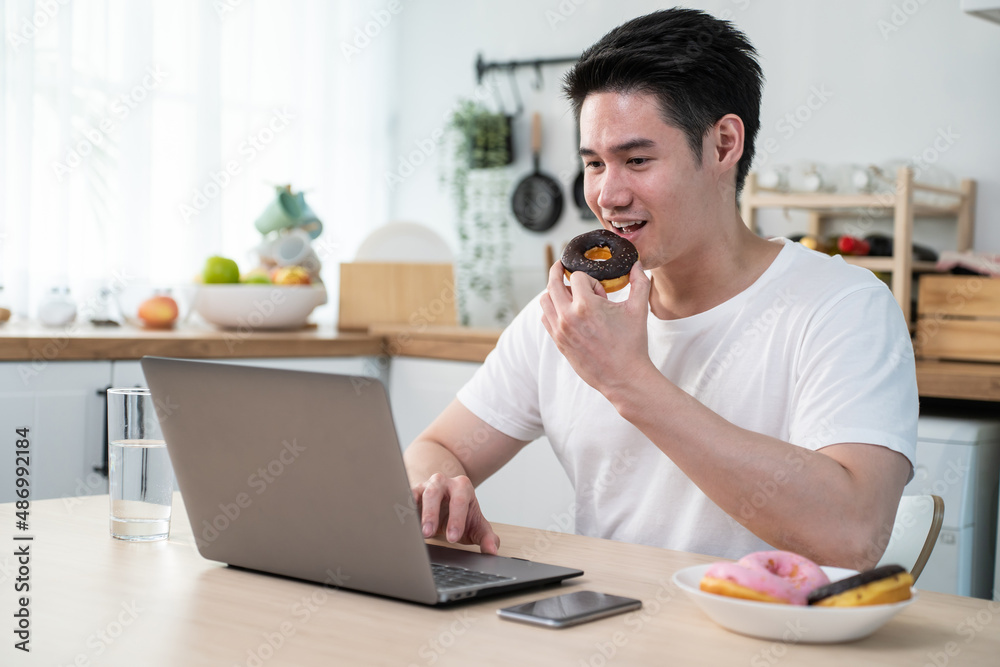 亚洲商人在家工作时吃不健康的垃圾食品。