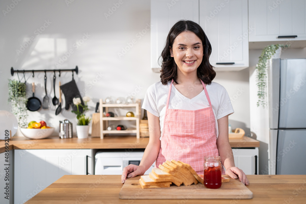 Portrait of attractive woman making sandwich for breakfast in morning. 