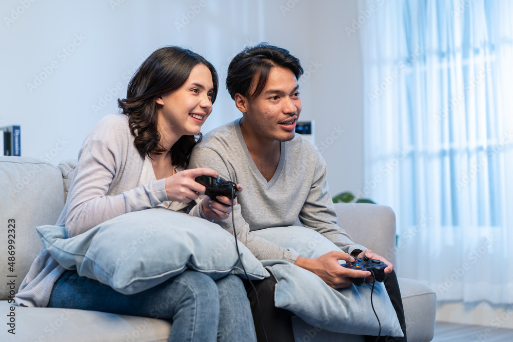 Asian young man and woman couple enjoy playing game together in house. 