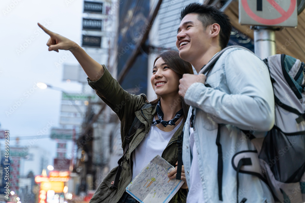 Asian active young couple travel in city for honeymoon trip at night.