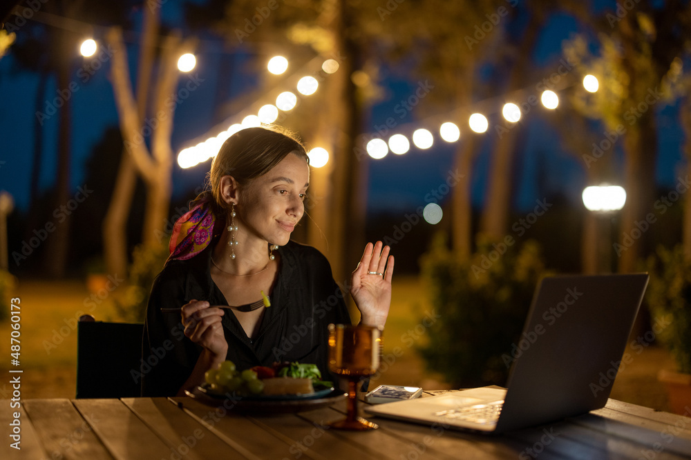 高加索女子晚上在户外用笔记本电脑看东西。年轻女子坐着