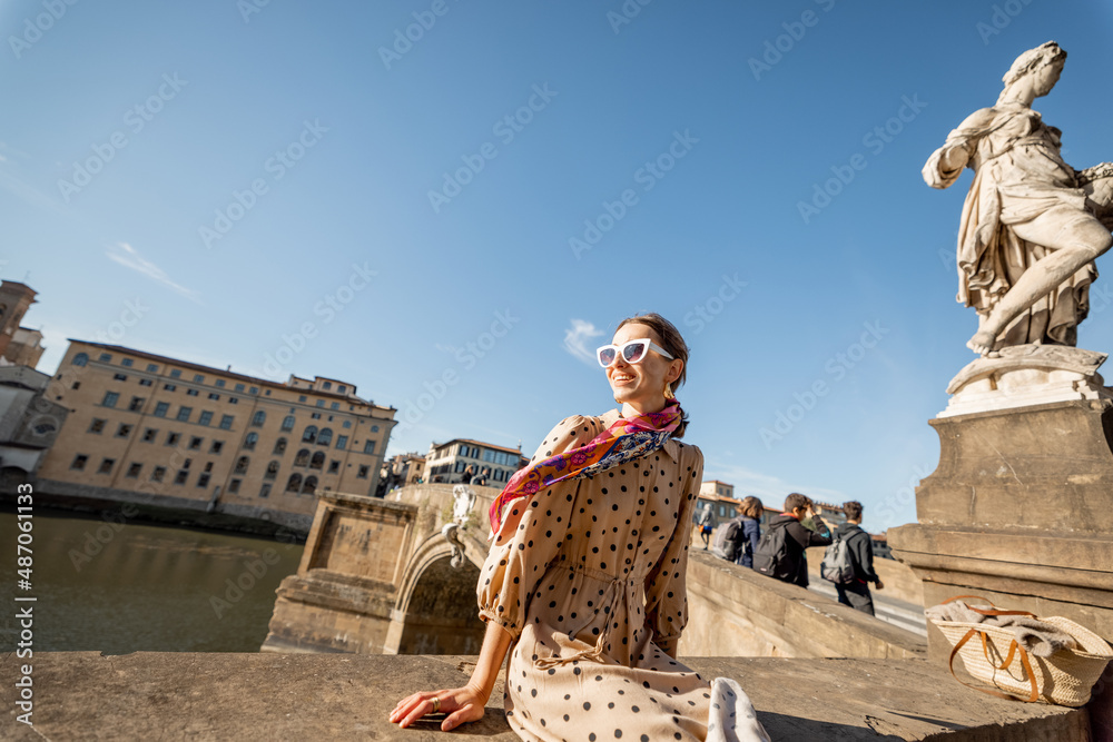 年轻的女人坐在阿诺河畔，在佛罗伦萨的老城区旅行。快乐的旅行者v