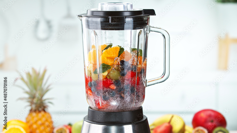 Mixing pieces of fruits and in blender. Preparation of healthy drink.