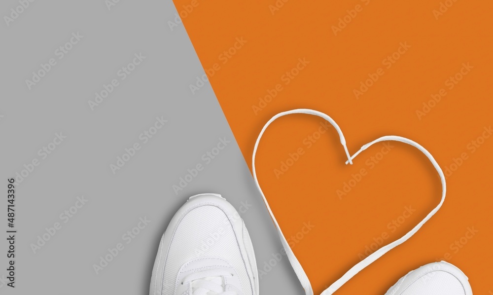 Two mens and womens stylish boots on color background. Laces in heart shape.