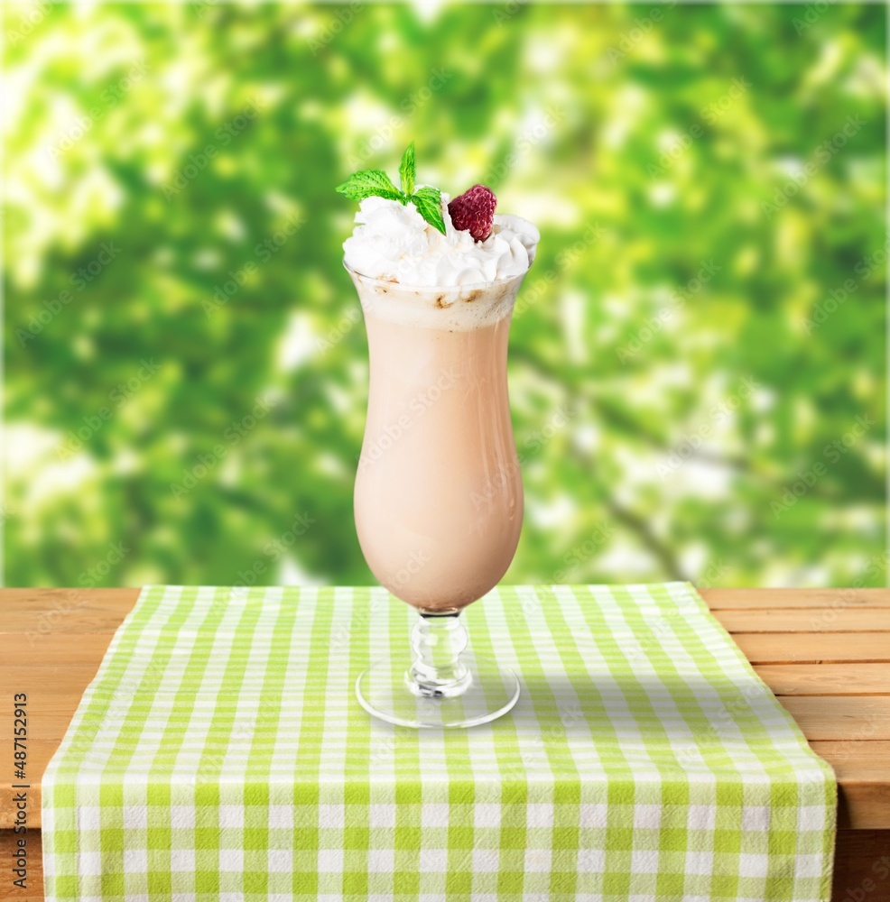 A glass of healthy strawberry smoothie with whipping cream on the desk