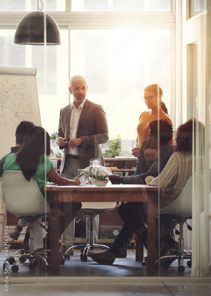 Sharing his business acumen. Shot of a group of coworkers in a boardroom meeting.