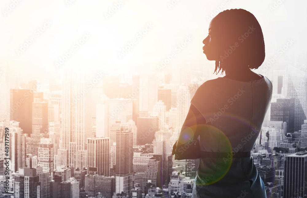 Overlooking a city filled with possibility. Rearview shot of a young businesswoman looking out from 