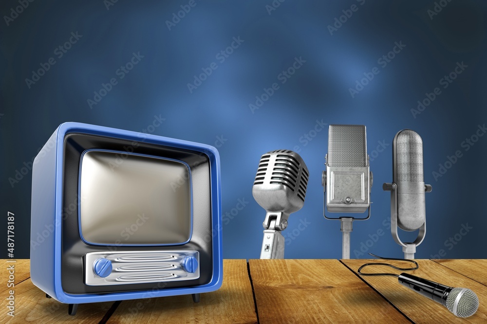 Retro outdated analog television and old microphones on wooden table