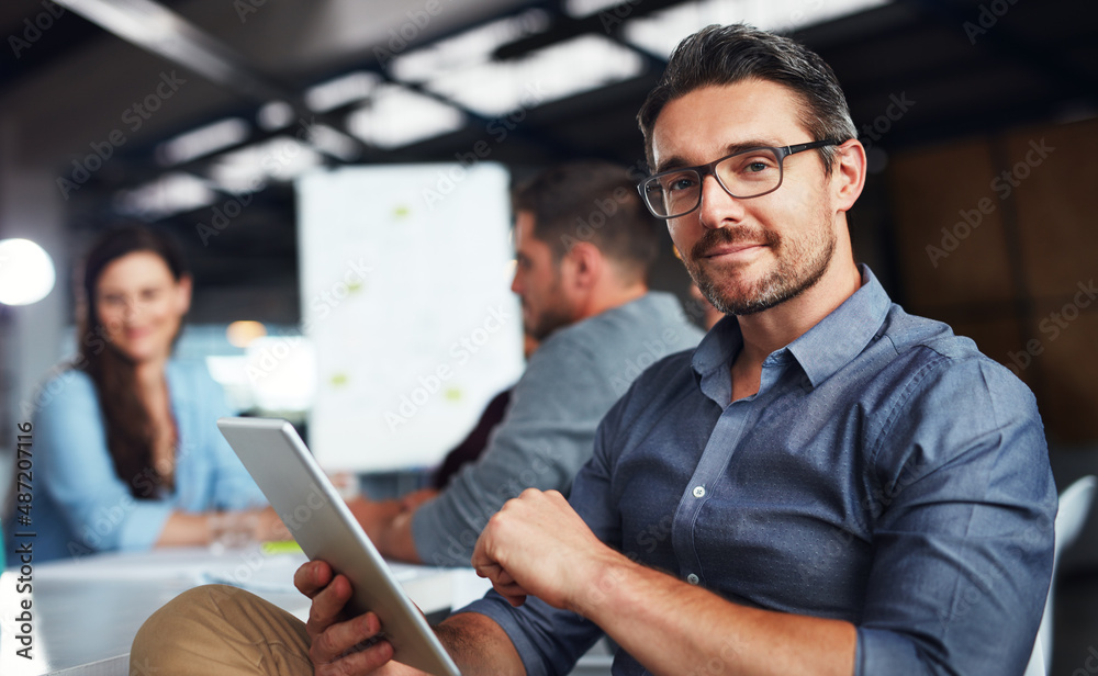 The creative process. Portrait of a man sitting at a table in an office using a digital tablet with 