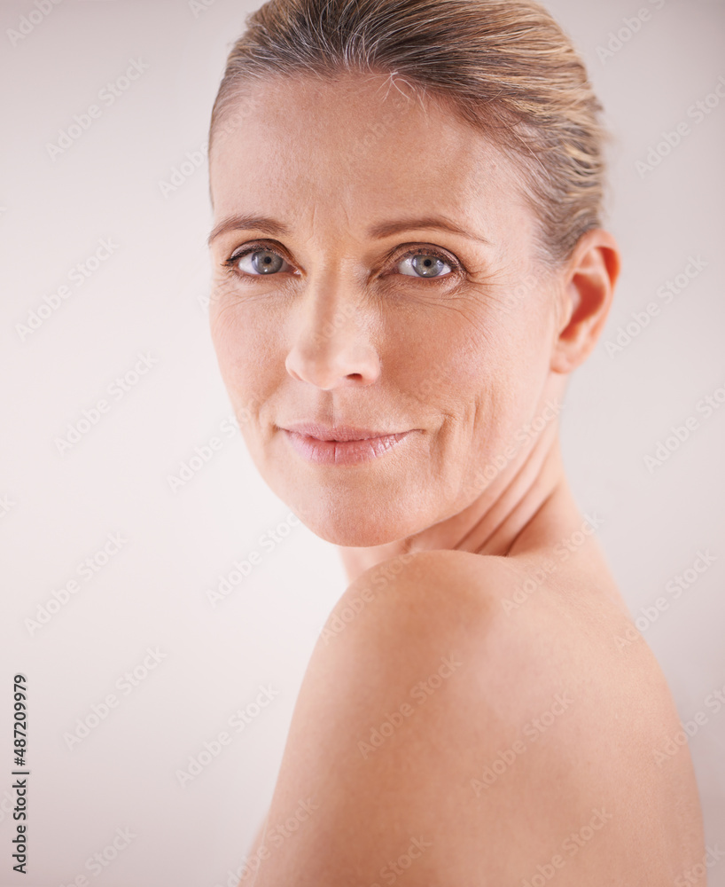 You can tell she loves her skin. Cropped studio shot of a beautiful mature woman looking over her sh