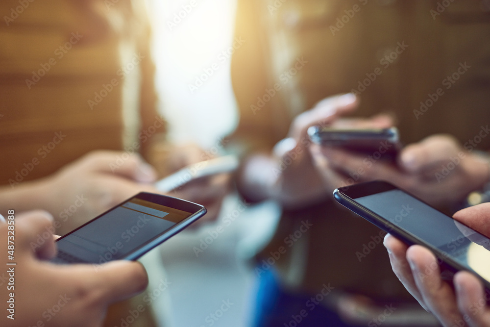 Its one connected world were living in. Cropped shot of a group of colleagues using their smart phon