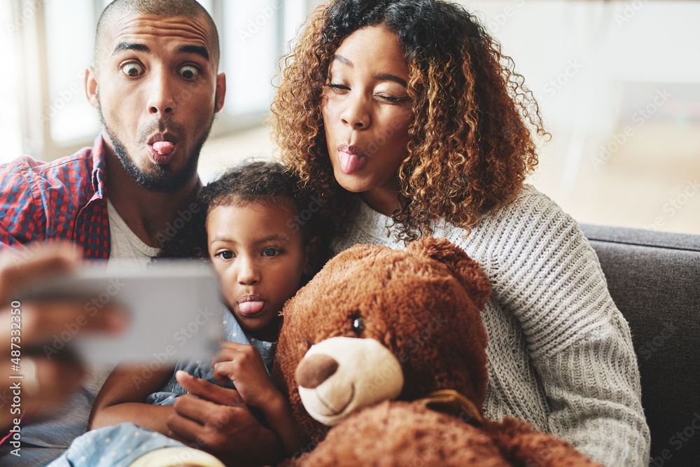 Tongue out everybody. Cropped shot of a happy young family of three posing for a selfie together in 