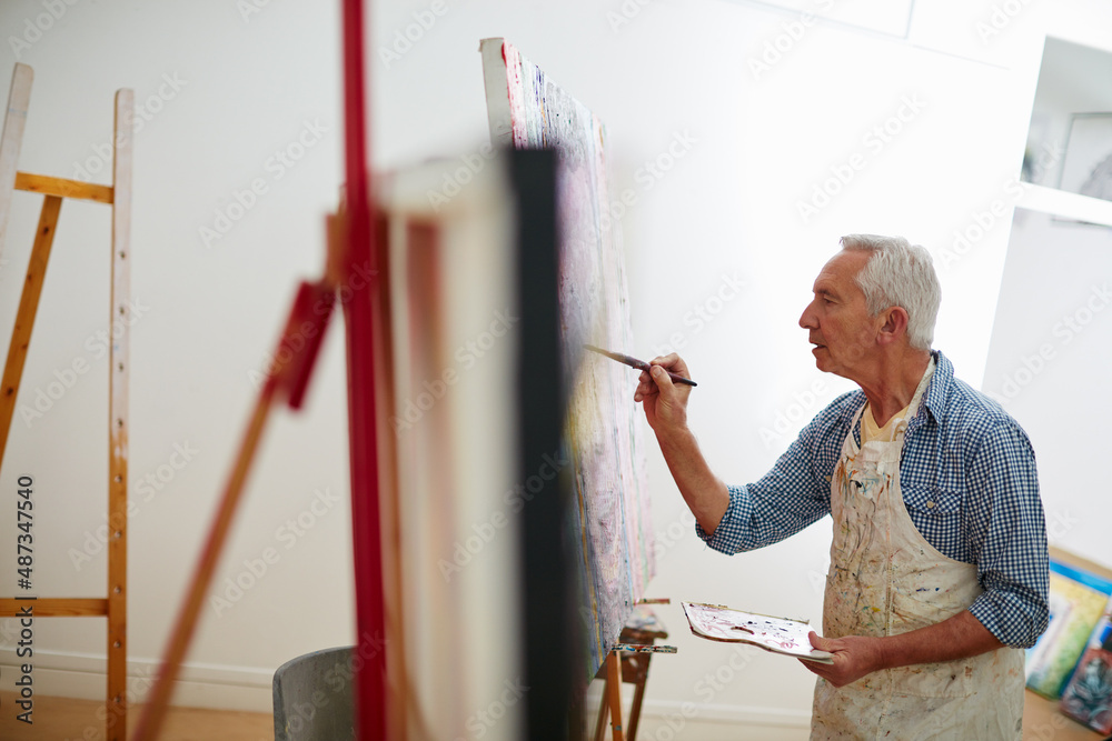 Art is the proper taste of life. Shot of a senior man working on a painting at home.