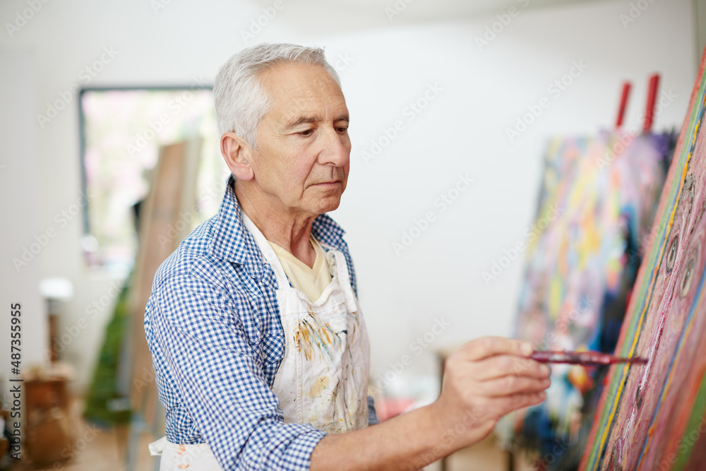 The creative adult is the child who survived. Shot of a senior man working on a painting at home.