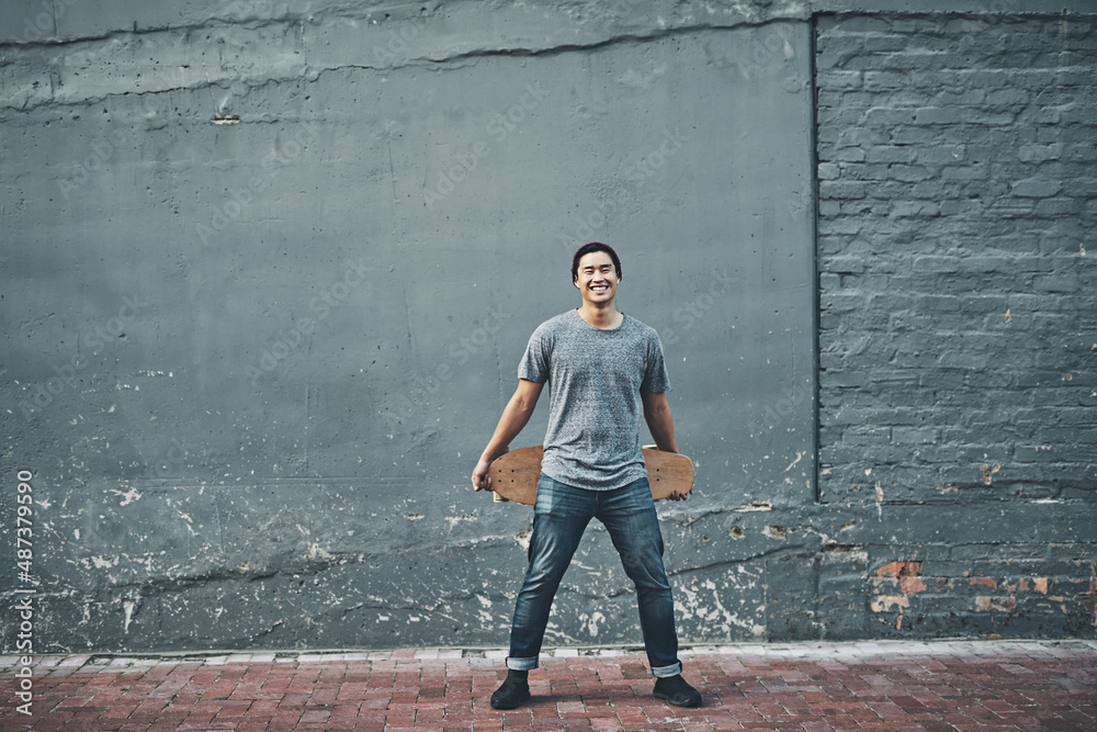 Take to the streets. Shot of a young man holding a skateboard outside.