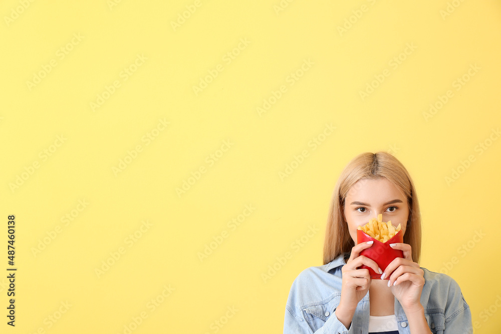 Young woman with french fries on yellow background