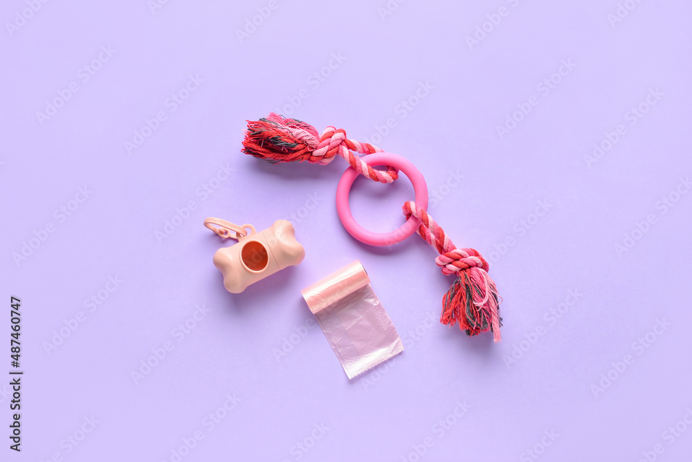 Dispenser, pet waste bags and toy on lilac background