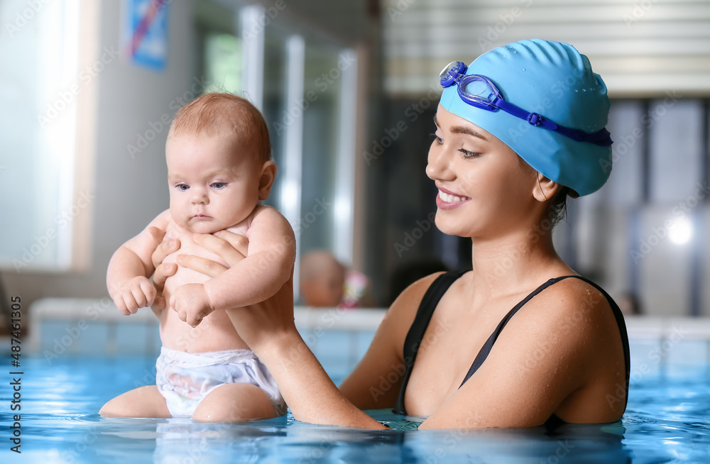 Swimming coach and adorable baby in pool