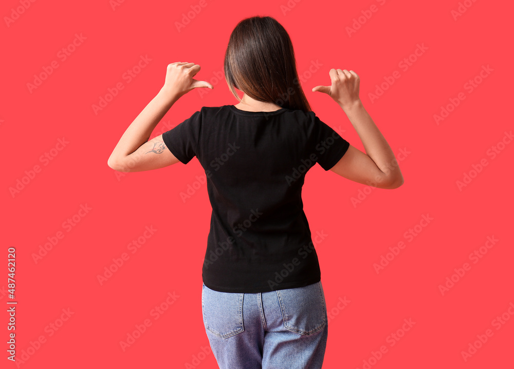 Young woman in blank t-shirt on color background, back view