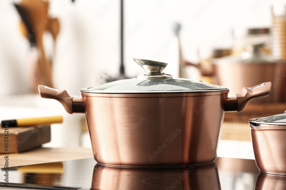 Shiny copper cooking pot on stove in kitchen, closeup