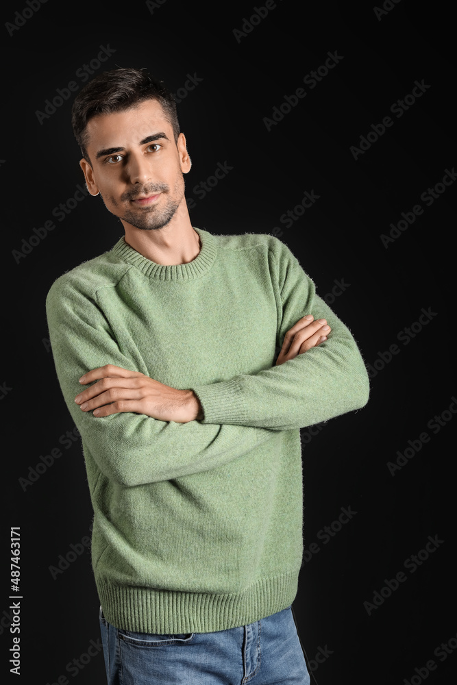 Handsome young man in knitted sweater on dark background