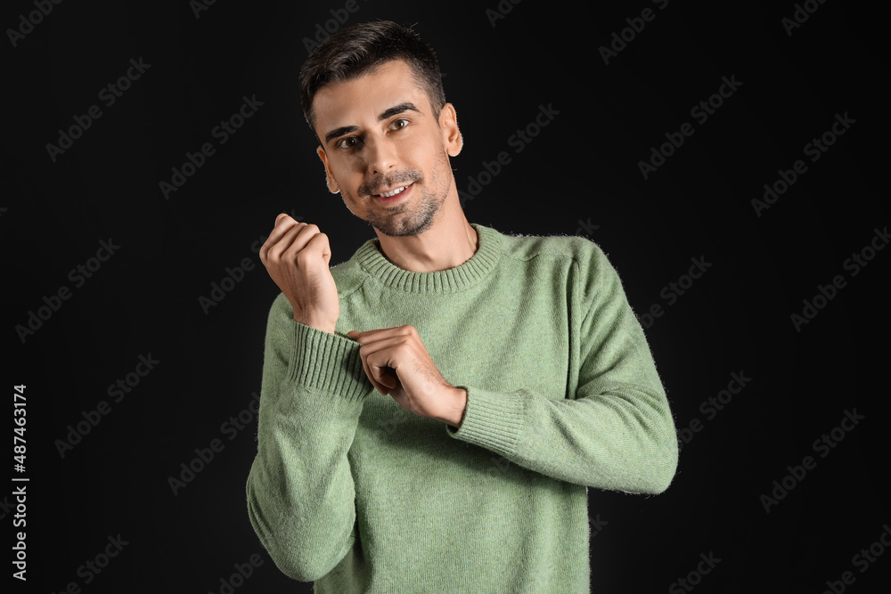 Handsome young man in knitted sweater on dark background