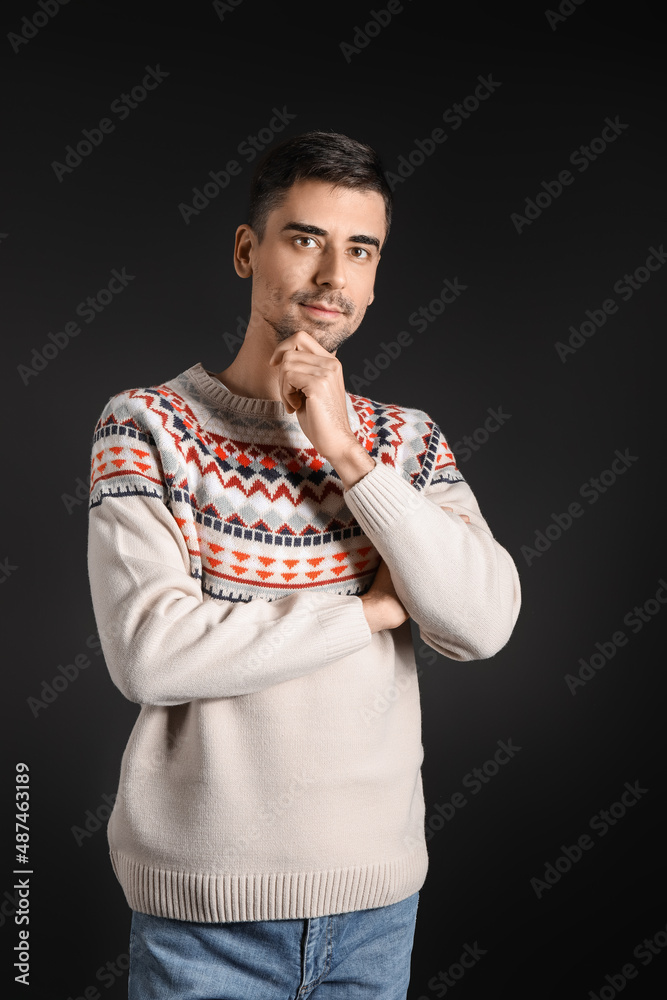 Handsome young man in knitted sweater on dark background