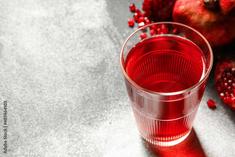 Glass of delicious pomegranate juice on light background