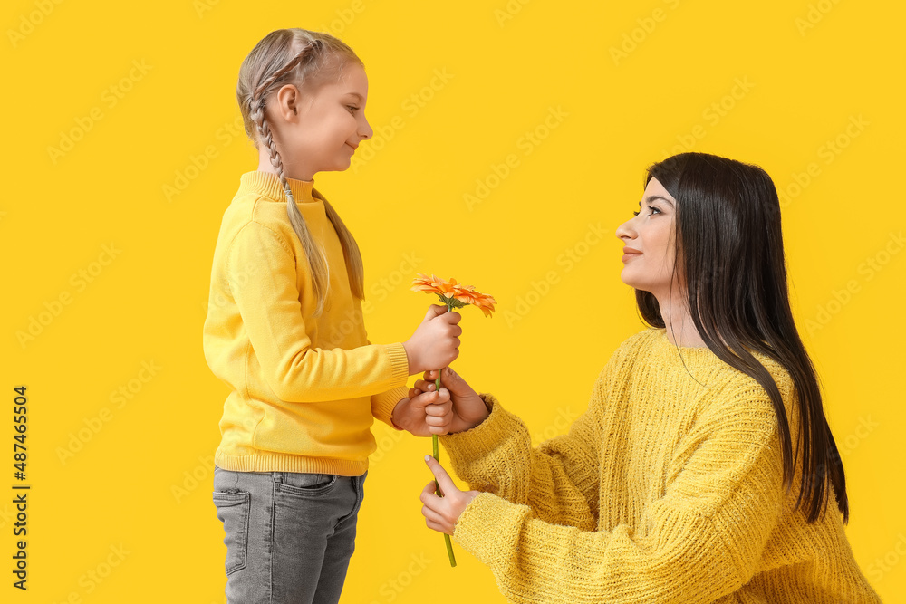 Little girl and her mother with flower on yellow background