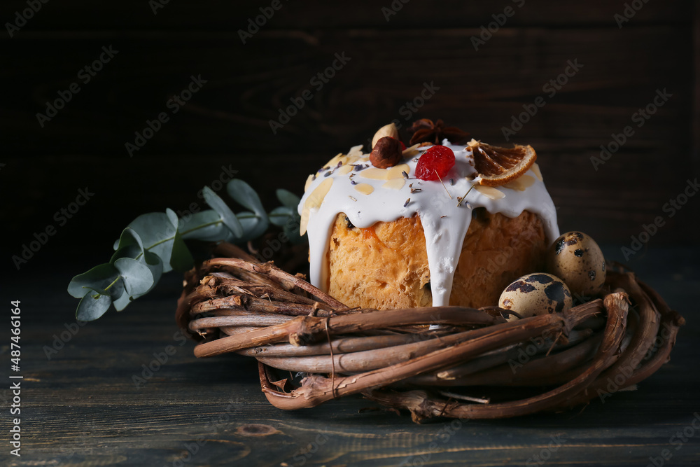 Basket with delicious Easter cake and eggs on black wooden background