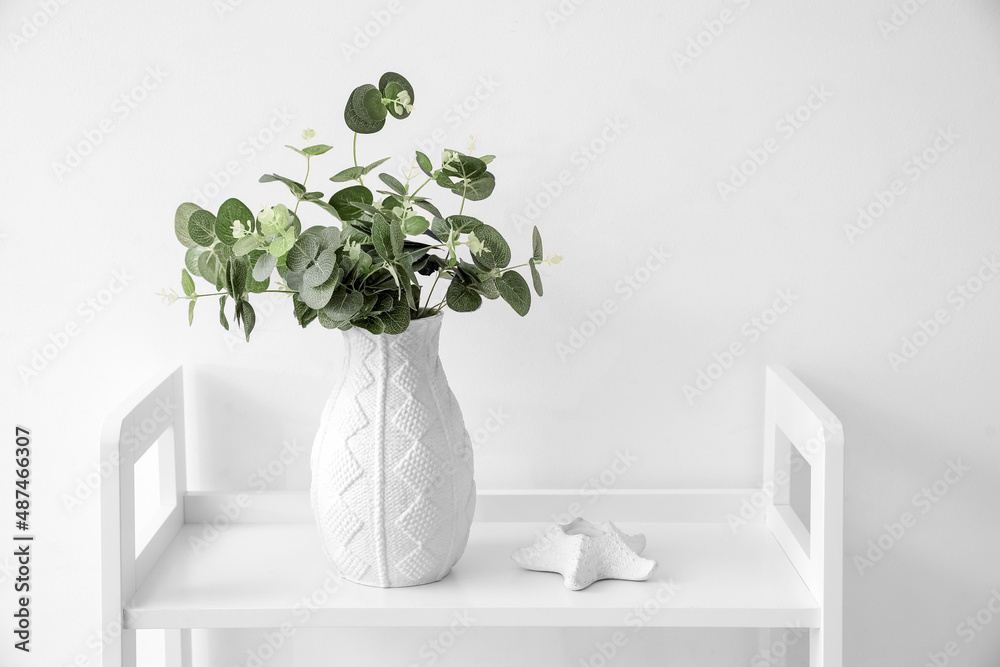 Vase with eucalyptus branches on table