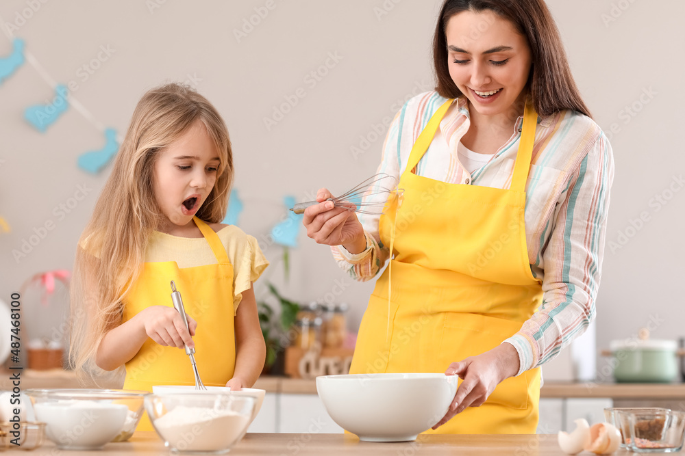 Little girl with her mother preparing dough for Easter cake in kitchen