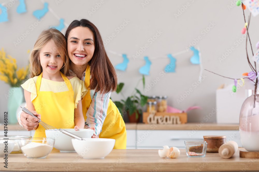 Little girl with her mother preparing dough for Easter cake in kitchen