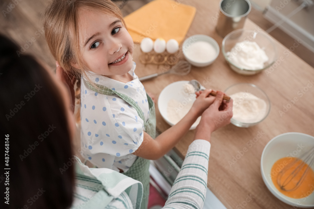 Little girl with her mother preparing dough for Easter cake in kitchen