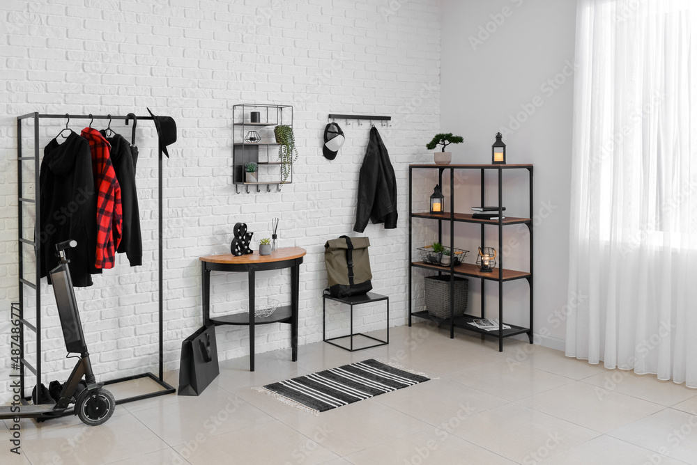 Stylish interior of room with modern electric scooter and hangers with clothes