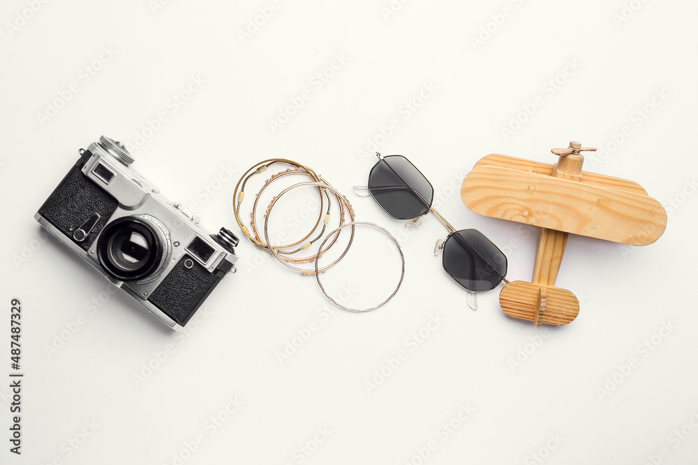 Stylish sunglasses, bracelets, photo camera and wooden plane on white background