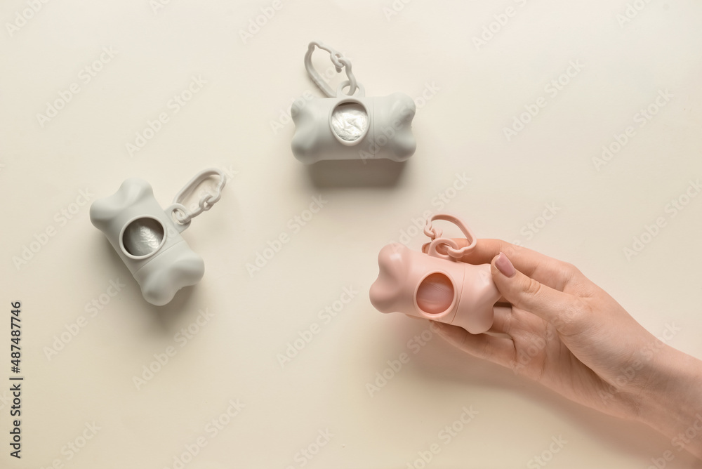 Female hand with pet waste bags on color background, closeup