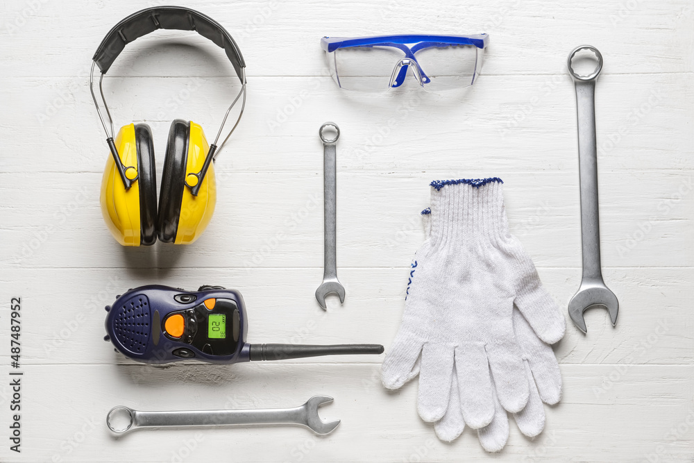 Safety equipment with builders tools and radio transmitter on white wooden background