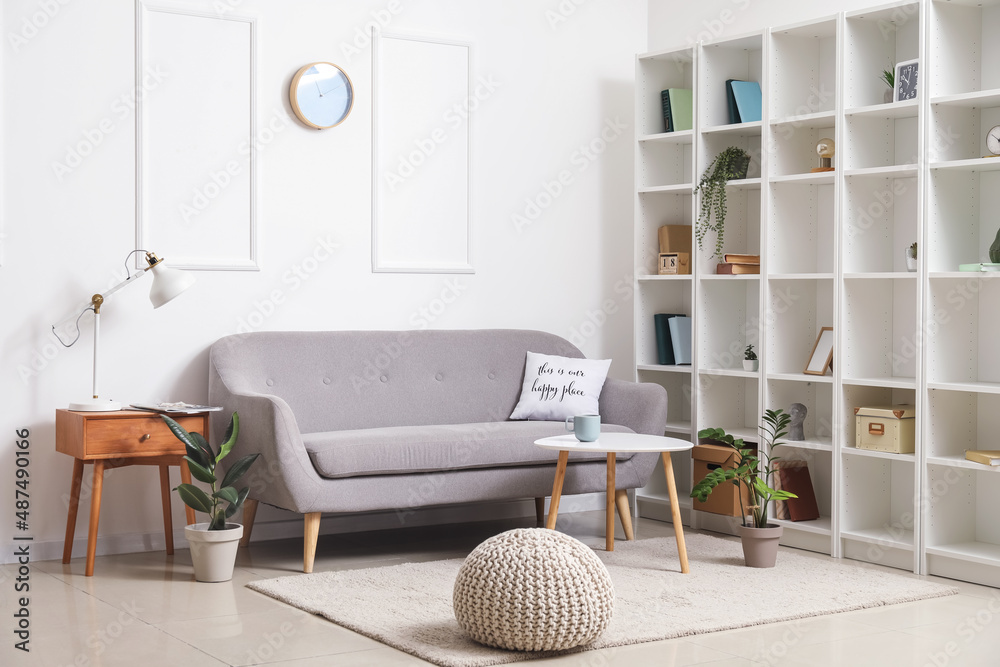 Interior of stylish living room with grey sofa and shelving unit