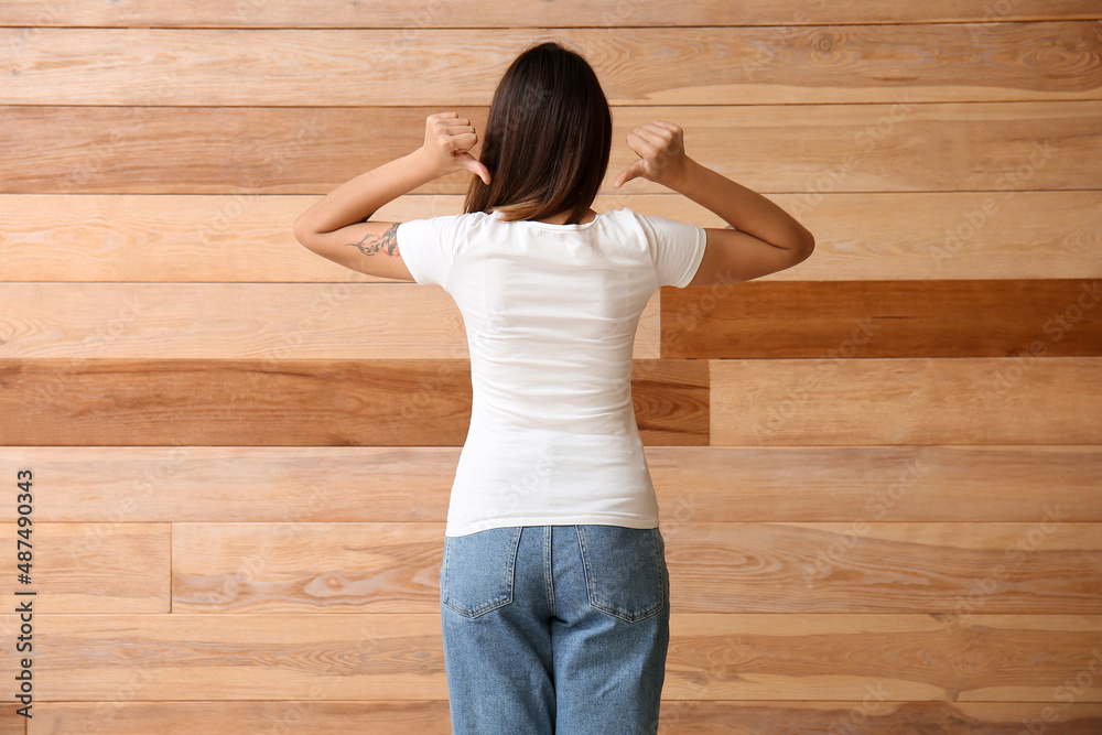 Young woman in blank t-shirt on wooden background, back view